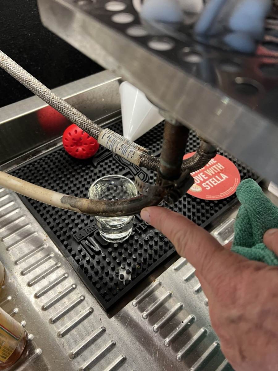 Venus technician inspecting a bar soda gun station and drain line during a restaurant service call